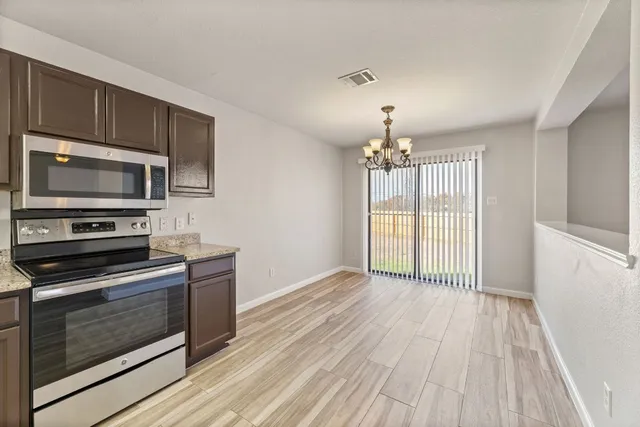 a view of a kitchen with a stove wooden cabinets and entryway