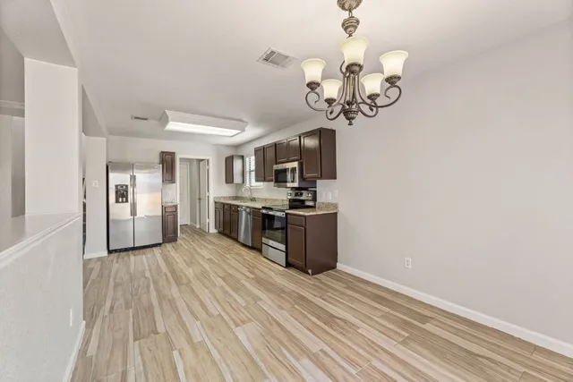 a kitchen with stainless steel appliances granite countertop a dishwasher a stove top oven a sink dishwasher and wooden floor