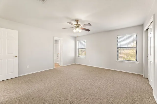 a view of an empty room with chandelier fan
