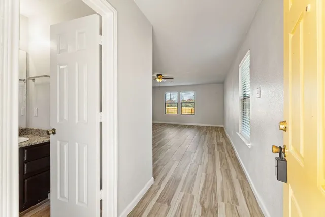 a view of a hallway with wooden floor and a bathroom