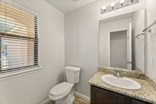a bathroom with a granite countertop sink toilet and mirror