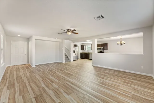 a view of a livingroom with wooden floor and kitchen