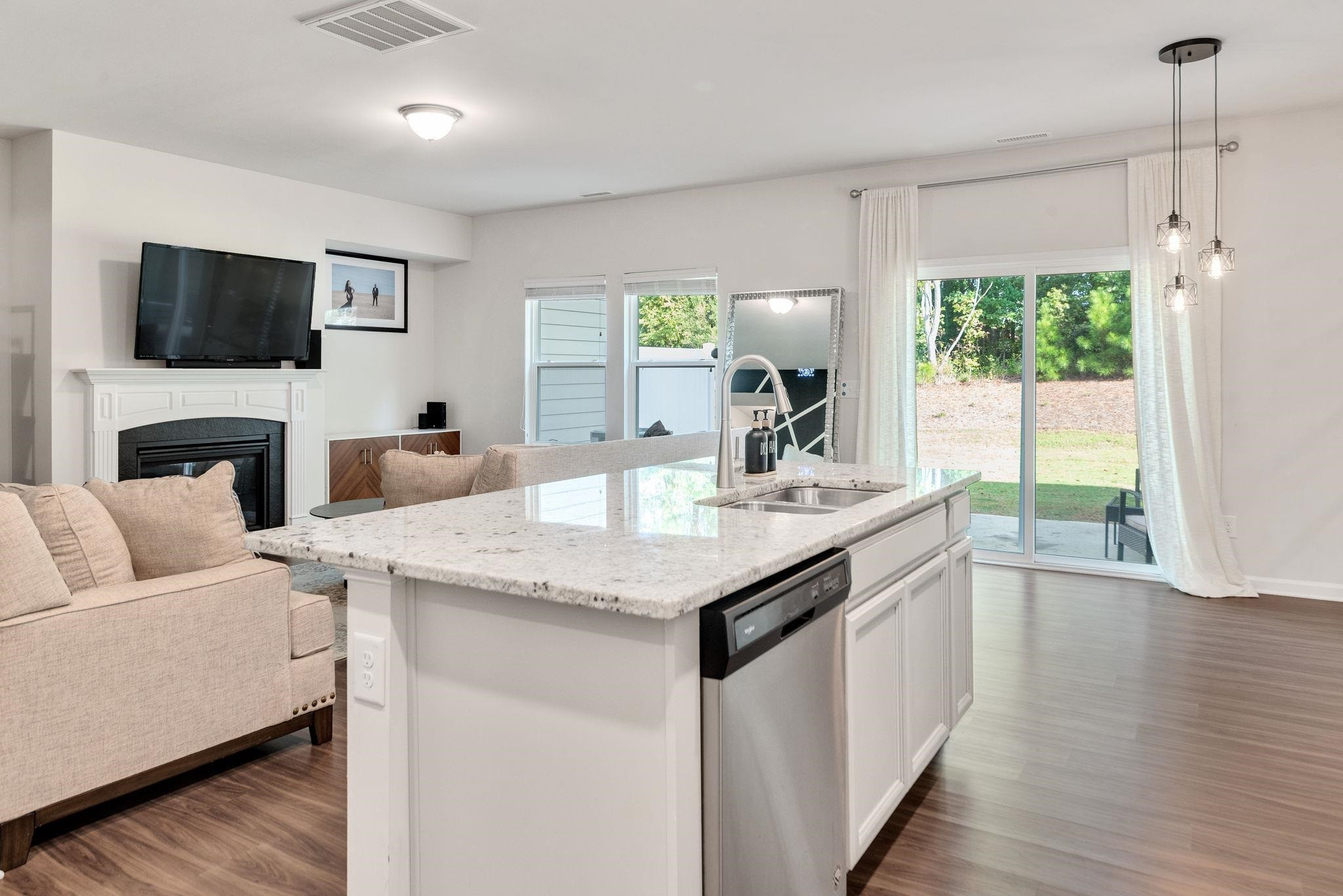 3422 Dropseed Drive Apex, NC 27502 - Photo 17 of 40 a view of living room with granite countertop couches a flat screen tv and a fireplace