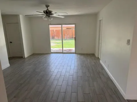 a view of an empty room with wooden floor and a window