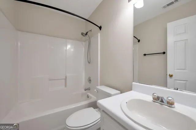 a bathroom with a bathtub shower sink vanity mirror and toilet