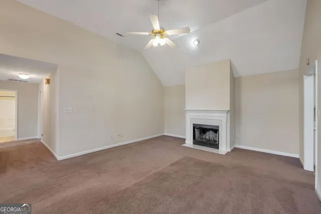 an empty room with a fireplace and a ceiling fan