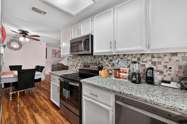 a kitchen with granite countertop a sink a stove and cabinets