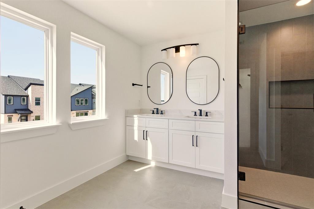 8902 Lowell Street Rowlett, TX 75089 - Photo 15 of 32 This bathroom features a double vanity with white cabinetry, black hardware, and two oval mirrors