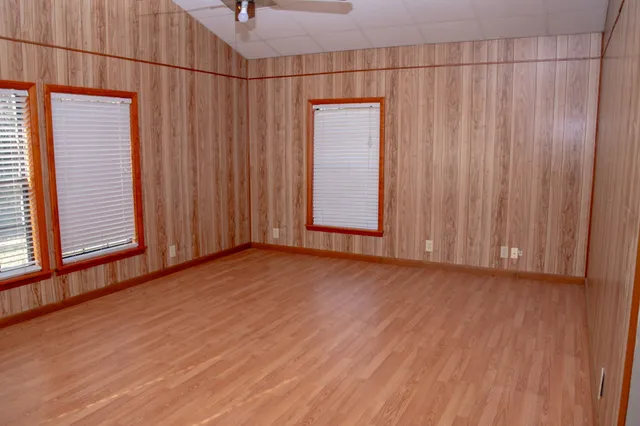 an empty room with wooden floor and windows