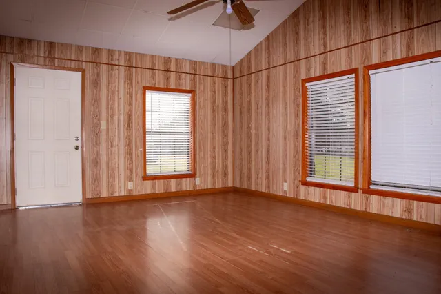 a view of an empty room with wooden floor and a window