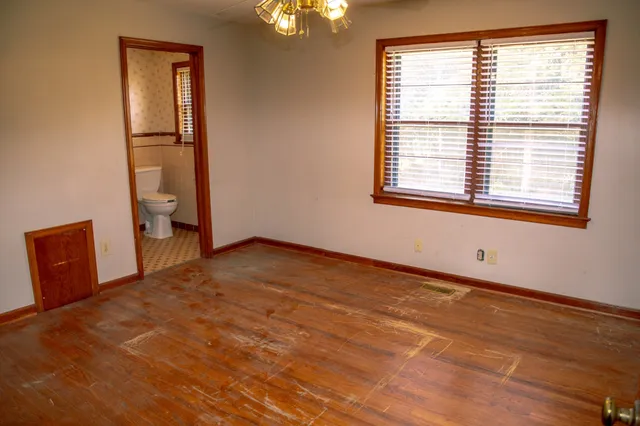 a view of an empty room with a window and wooden floor