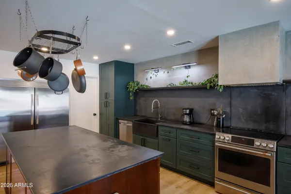 a kitchen with stainless steel appliances granite countertop a sink a stove and a refrigerator