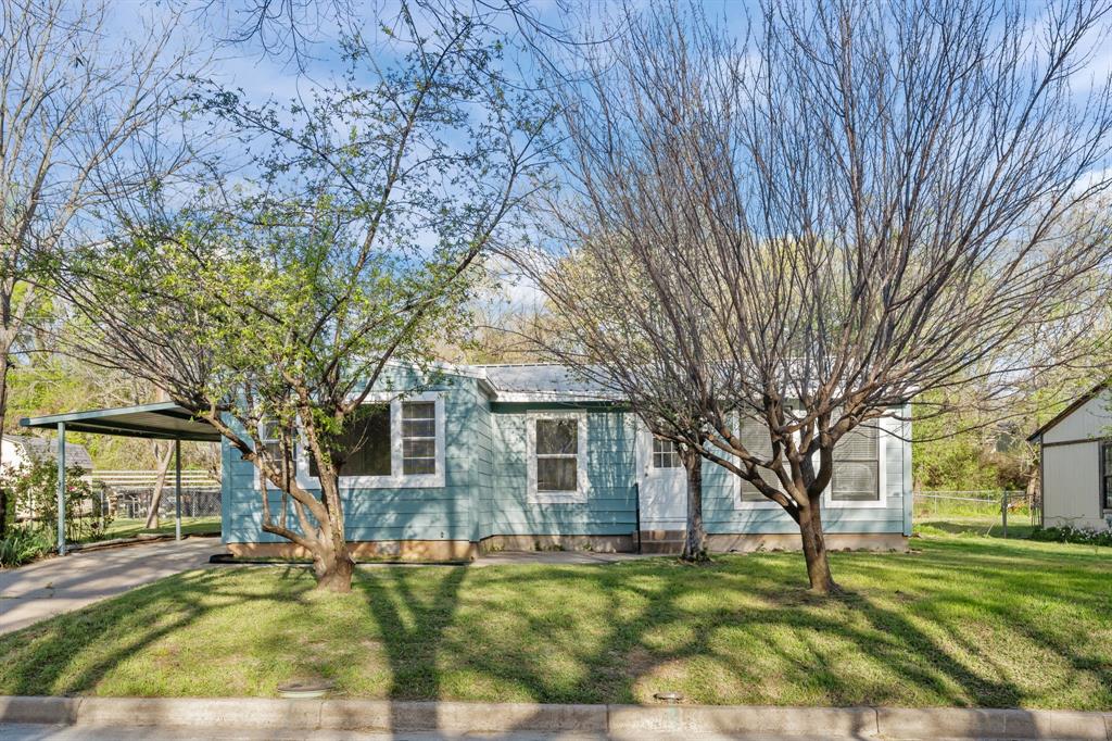 217 Clinton Drive Weatherford, TX 76086 - Photo 2 of 19 a view of a yard in front of a brick house with a large tree