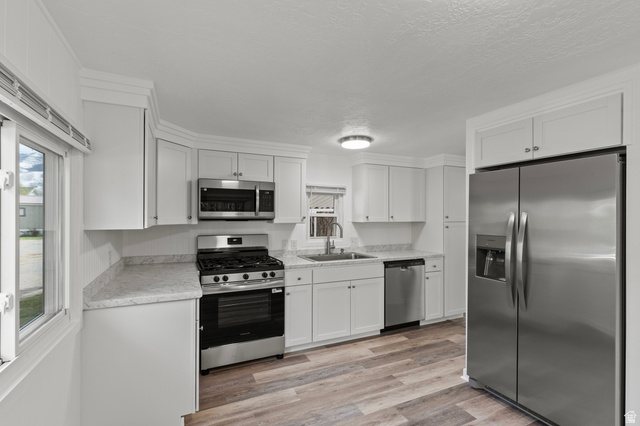 350 West 800 South, Unit 2 Logan, UT 84321 - Photo 5 of 22 Kitchen with stainless steel appliances, light countertops, white cabinets, light wood finished floors, and a textured ceiling