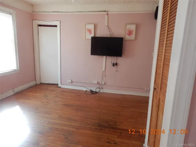 a view of room with wooden floor and flat screen tv