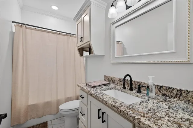 a bathroom with a granite countertop sink a toilet and a mirror