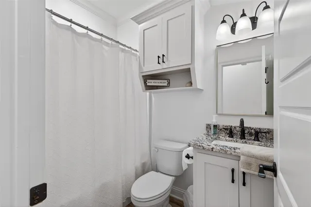 a bathroom with a granite countertop sink vanity mirror and toilet