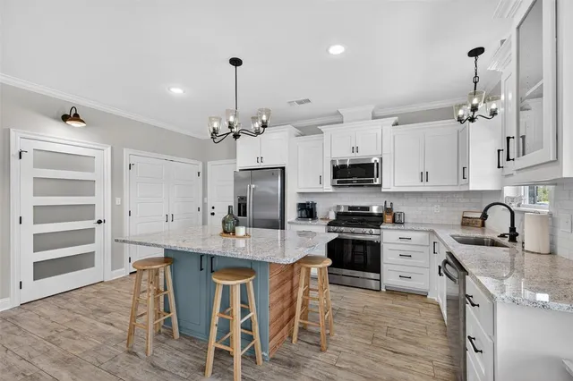 a kitchen with kitchen island granite countertop a sink a counter space appliances and cabinets