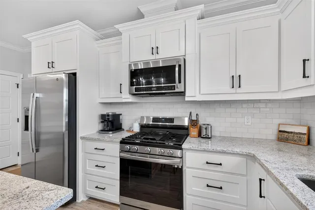 a kitchen with stainless steel appliances granite countertop white cabinets and a stove