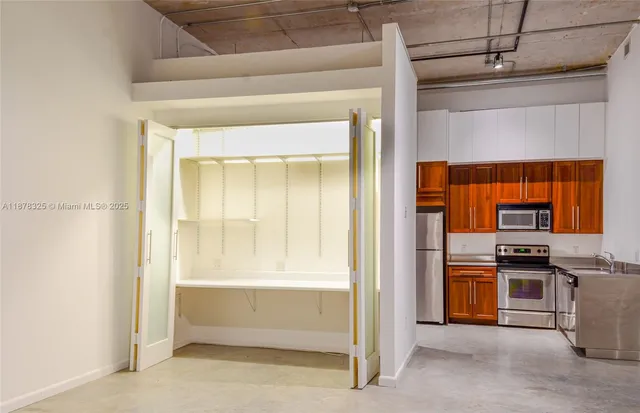 a view of an empty room and a kitchen