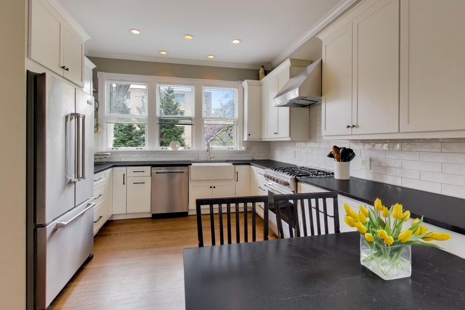 1235 Maple Avenue Evanston, IL 60202 - Photo 20 of 57 a kitchen with stainless steel appliances granite countertop a stove a sink a microwave a dining table and chairs