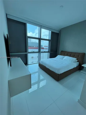 a bedroom with a bed and large window