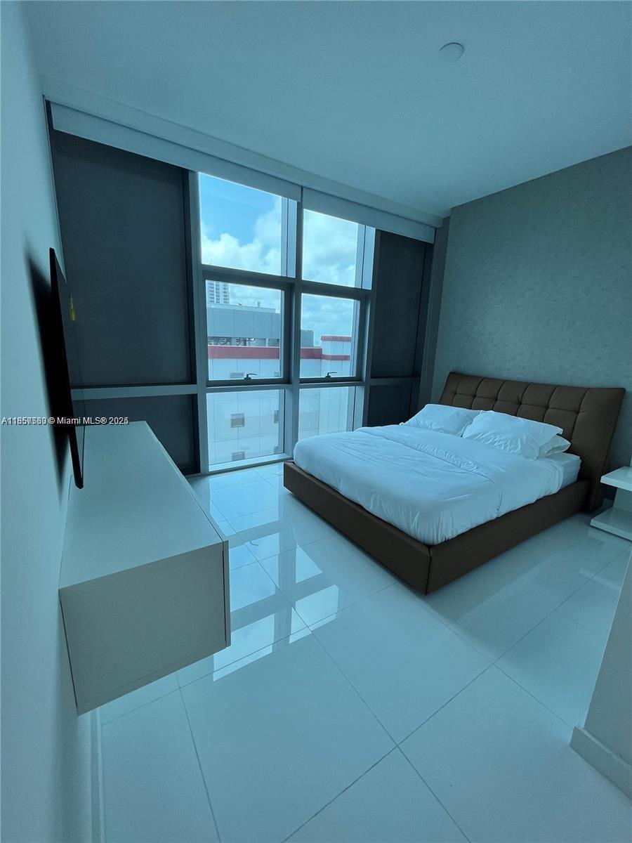 851 Northeast 1st Avenue, Unit 808 Miami, FL 33132 - Photo 11 of 23 a bedroom with a bed and large window