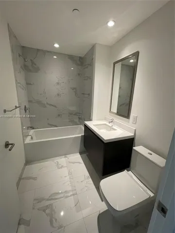 a bathroom with a bathtub sink mirror and toilet