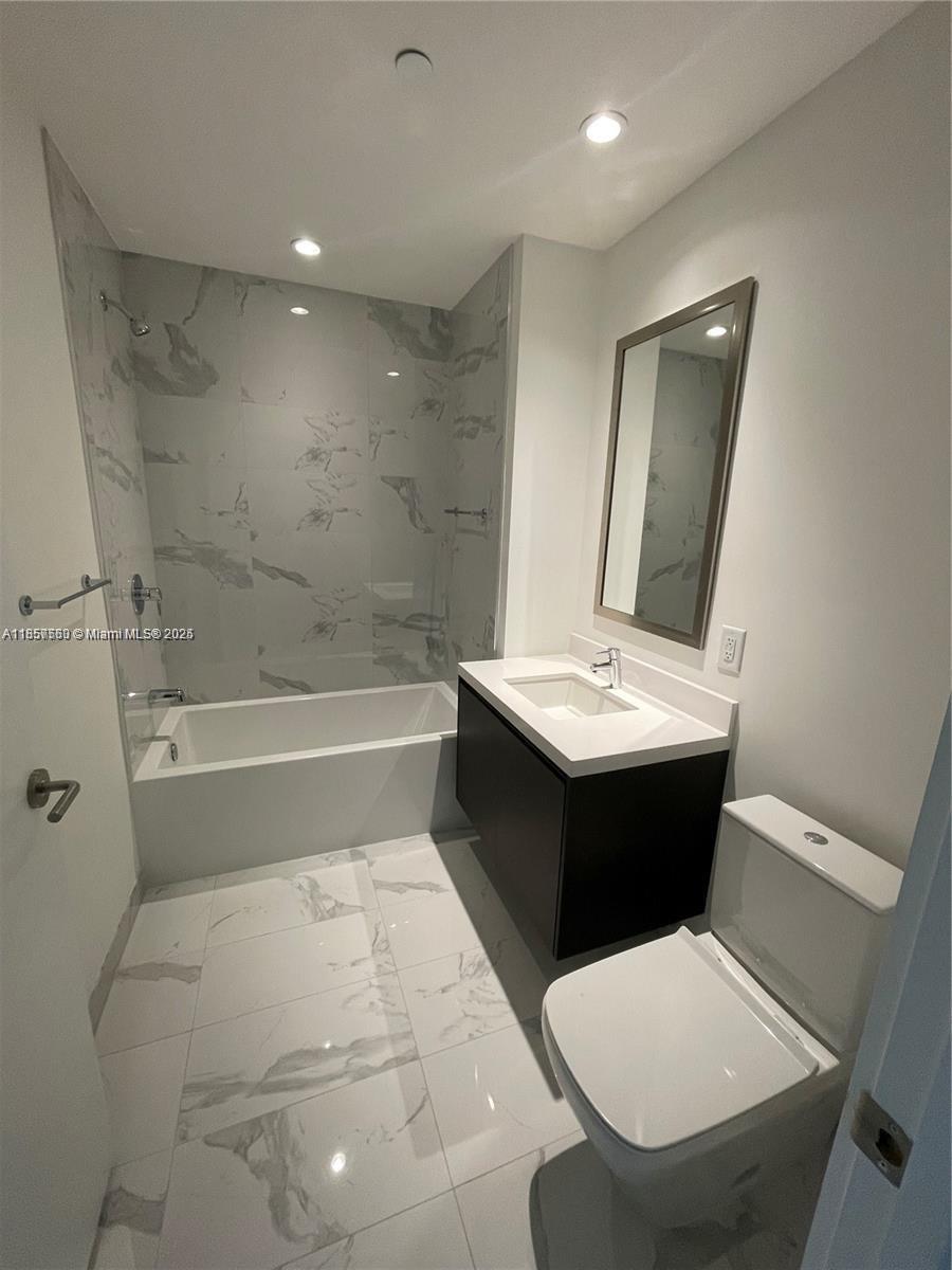 851 Northeast 1st Avenue, Unit 808 Miami, FL 33132 - Photo 12 of 23 a bathroom with a bathtub sink mirror and toilet
