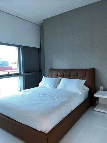 a large bed sitting in a bedroom next to a window
