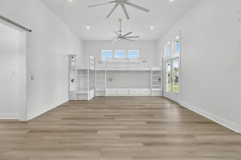 a large kitchen with kitchen island a stove a sink dishwasher a refrigerator and white cabinets with wooden floor