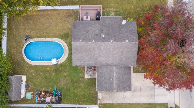 an aerial view of a house with a swimming pool and large trees