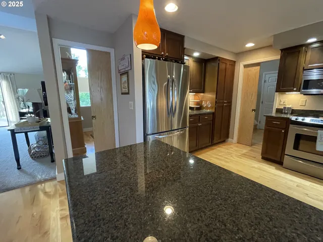 a kitchen with stainless steel appliances granite countertop a refrigerator a stove and a sink