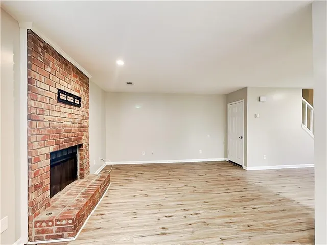 a view of an empty room with wooden floor fireplace and a window