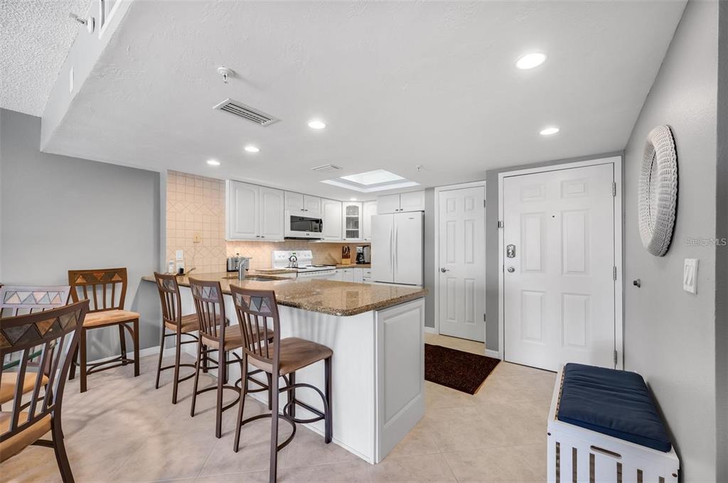 12924 Gulf Boulevard, Unit 510 Madeira Beach, FL 33708 - Photo 22 of 61 a kitchen with stainless steel appliances kitchen island granite countertop a table and chairs in it