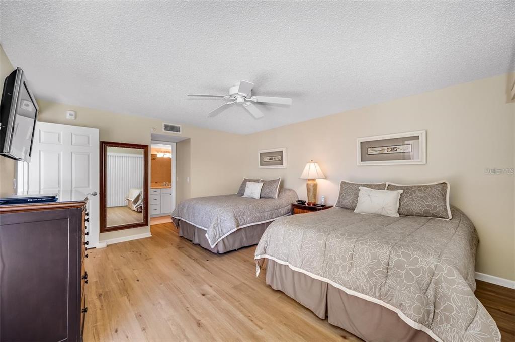 12924 Gulf Boulevard, Unit 510 Madeira Beach, FL 33708 - Photo 33 of 61 a spacious bedroom with two beds and a chandelier