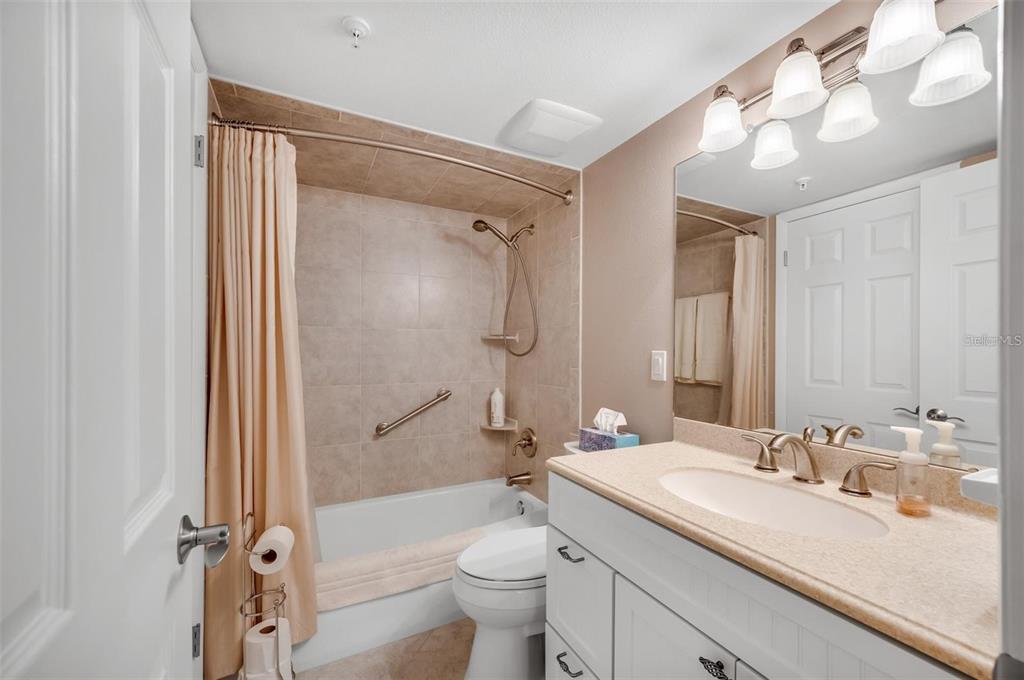 12924 Gulf Boulevard, Unit 510 Madeira Beach, FL 33708 - Photo 43 of 61 a bathroom with a granite countertop sink toilet mirror and shower