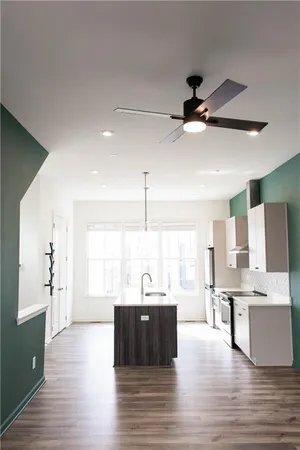 a large kitchen with stainless steel appliances kitchen island granite countertop a sink and a large window