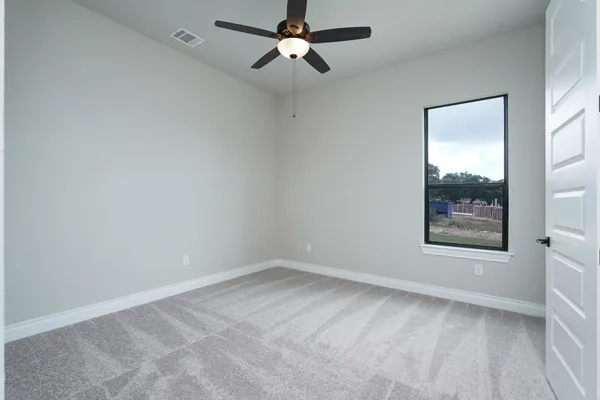 an empty room with a window and a fan