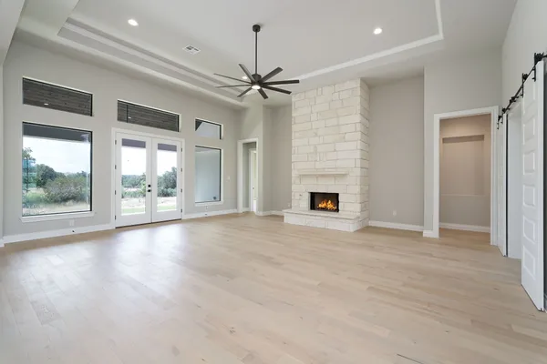 an empty room with wooden floor fan and windows
