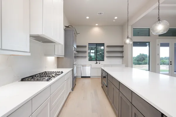 a large kitchen with stainless steel appliances kitchen island a large stove a sink dishwasher and white cabinets with wooden floor