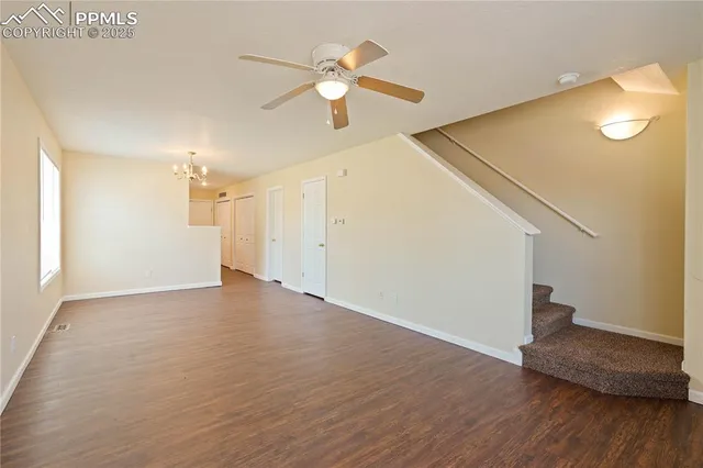 a view of an empty room with wooden floor and a ceiling fan