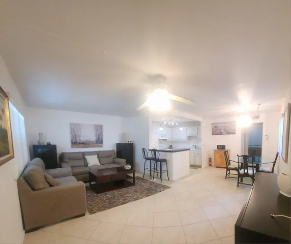 a living room with furniture and a dining table with kitchen view