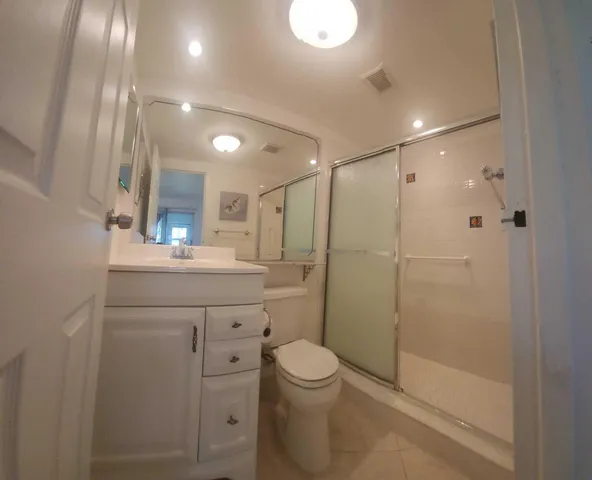 a bathroom with a shower a sink a toilet and mirror