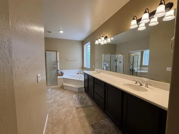 a spacious bathroom with a double vanity sink a mirror and a shower