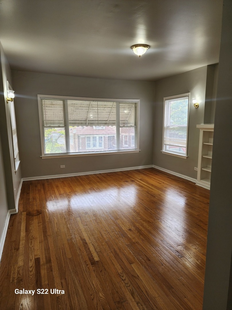 7823 South Evans Avenue, Unit 2 Chicago, IL 60619 - Photo 2 of 13 an empty room with wooden floor and windows