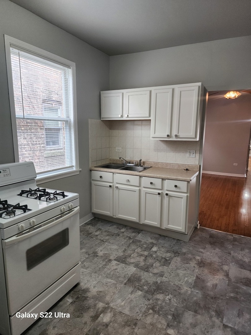 7823 South Evans Avenue, Unit 2 Chicago, IL 60619 - Photo 6 of 13 a kitchen with a stove top oven sink and cabinets