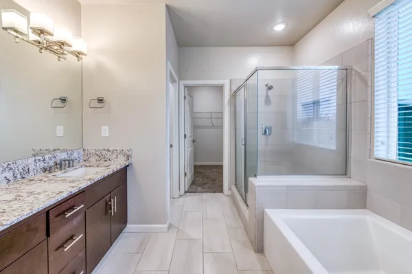 a spacious bathroom with a granite countertop tub shower double vanity and a sink
