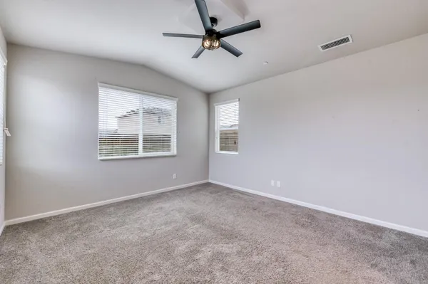 an empty room with windows and ceiling fan