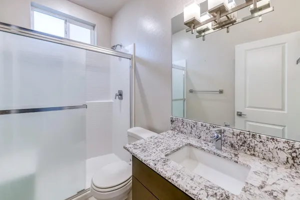a bathroom with a granite countertop sink a toilet and shower